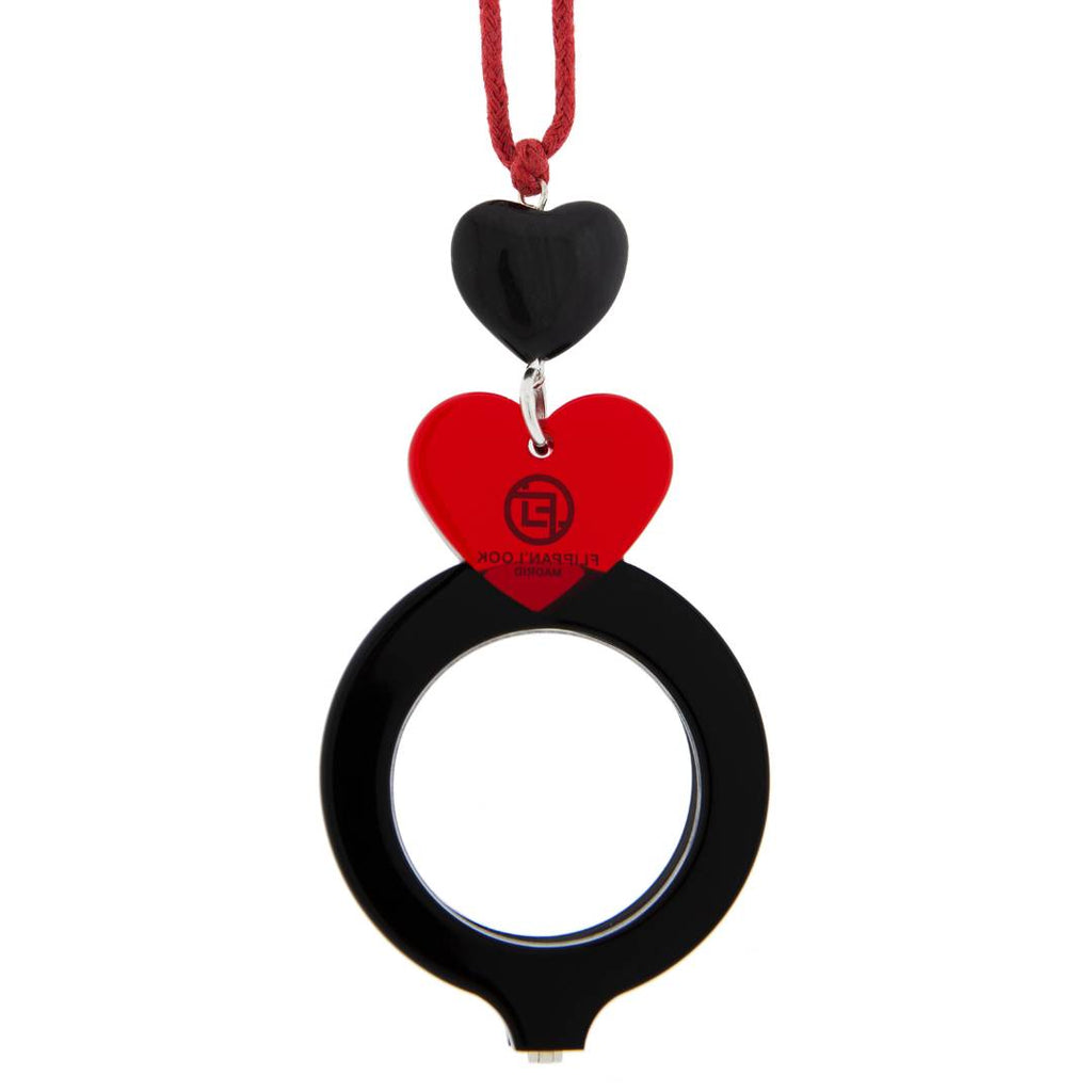 Colgante de acetato en negro y rojo tranparente, con una bisagra que hace que se transforme en gafas de lectura. Collar hecho en cordón de algodón rojo, abalorio de cristal en forma de corazón y fornituras plateadas.