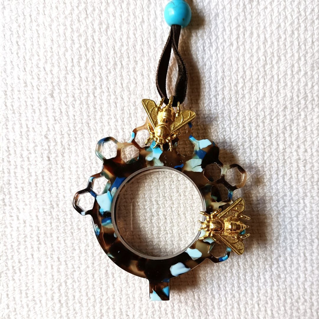Medallón-gafas de acetato en tonos carey y turquesas, realizado en acetato y con abejas metálicas en color dorad. Rematado con collar de terciopelo con abalorio en color turquesa.Transformable en gafas de lectura. Cerrado