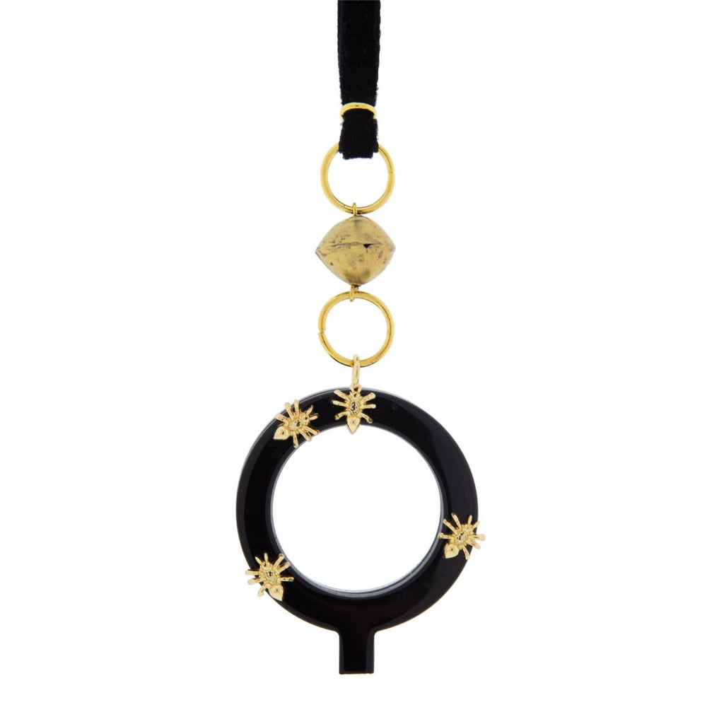 Colgante gafas Hormigas, realizado en acetato color negro con hormigas metálicas doradas y collar de terciopelo negro con fornituras  y abalorios dorados. El colgante tiene una bisagra que hace que se pueda desplegar y transformar en gafas de lectura.