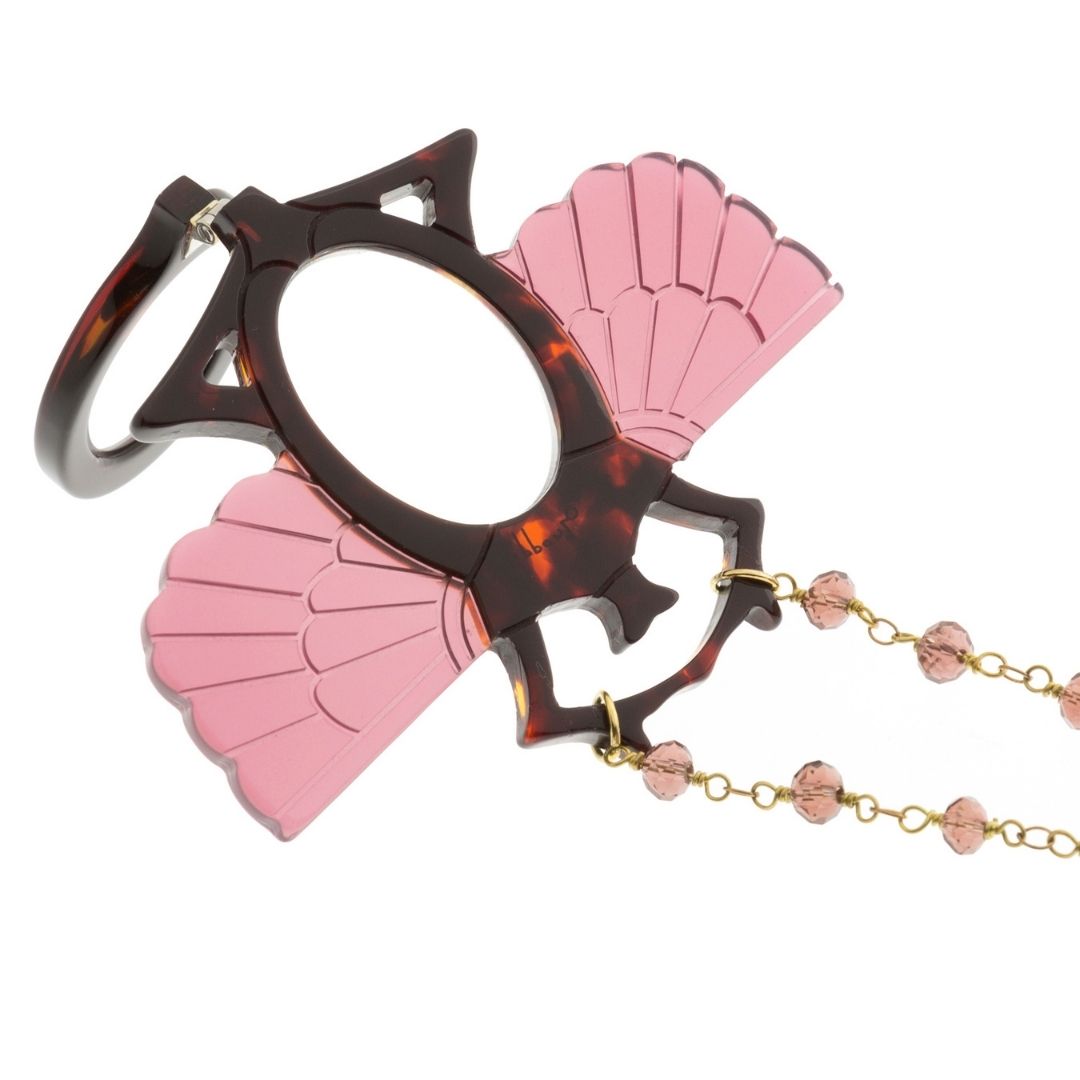 Colgante-gafas en forma de escarabajo egipcio. Realizado en combinación de acetato imitación carey con las alas en rosa transparente. Cadena de rosario en latón con cuentas de vidrio rosa. Una bisagra hace que se pueda transformar en gafas de lectura